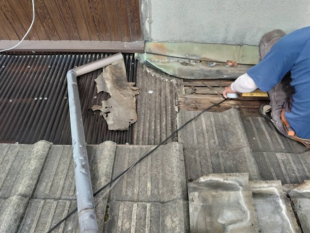 谷板金周辺の下地の劣化状況を確認しながら瓦を取り外す作業員の様子