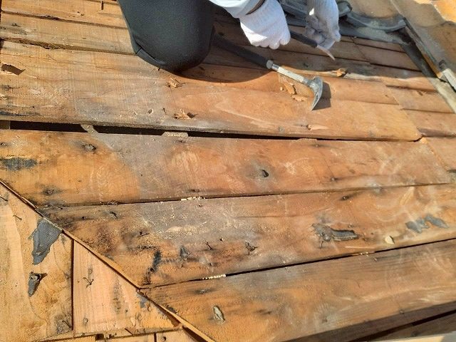 バールやノコギリを使って雨水で傷んだ野地板を切断・撤去している作業の様子