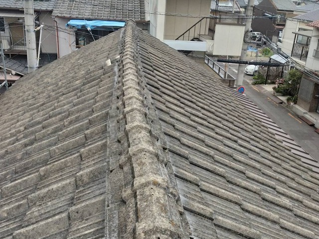 隣家のセメント瓦屋根の棟部が大きく歪んでいる状況