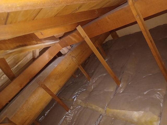 雨漏りの影響で野地板や木材にシミが生じている小屋裏の状況