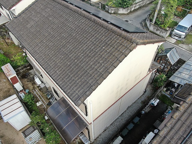 色あせが進んだモニエル瓦屋根の全景と太陽光パネルの設置状況