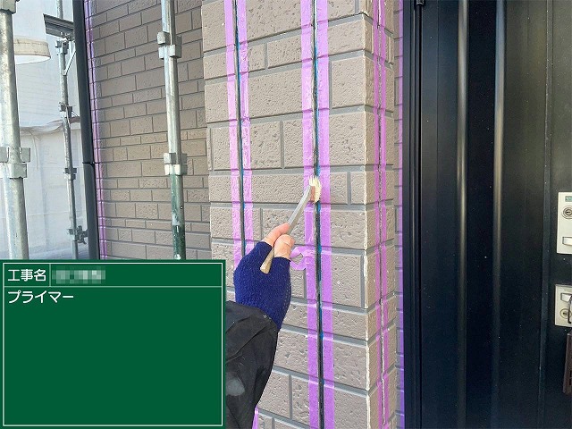 マスキングテープで養生したサイディング目地にプライマーを刷毛で塗布している様子