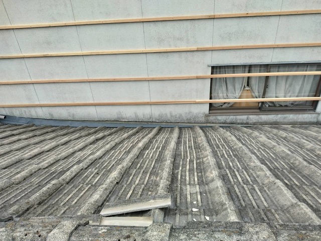 屋根のズレた瓦材が隣接する住宅の外壁へ滑り落ちるリスクがある様子